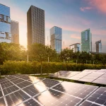 Comunità energetiche rinnovabili. Grattacieli al tramonto sullo sfondo e pannelli fotovoltaici in primo piano.